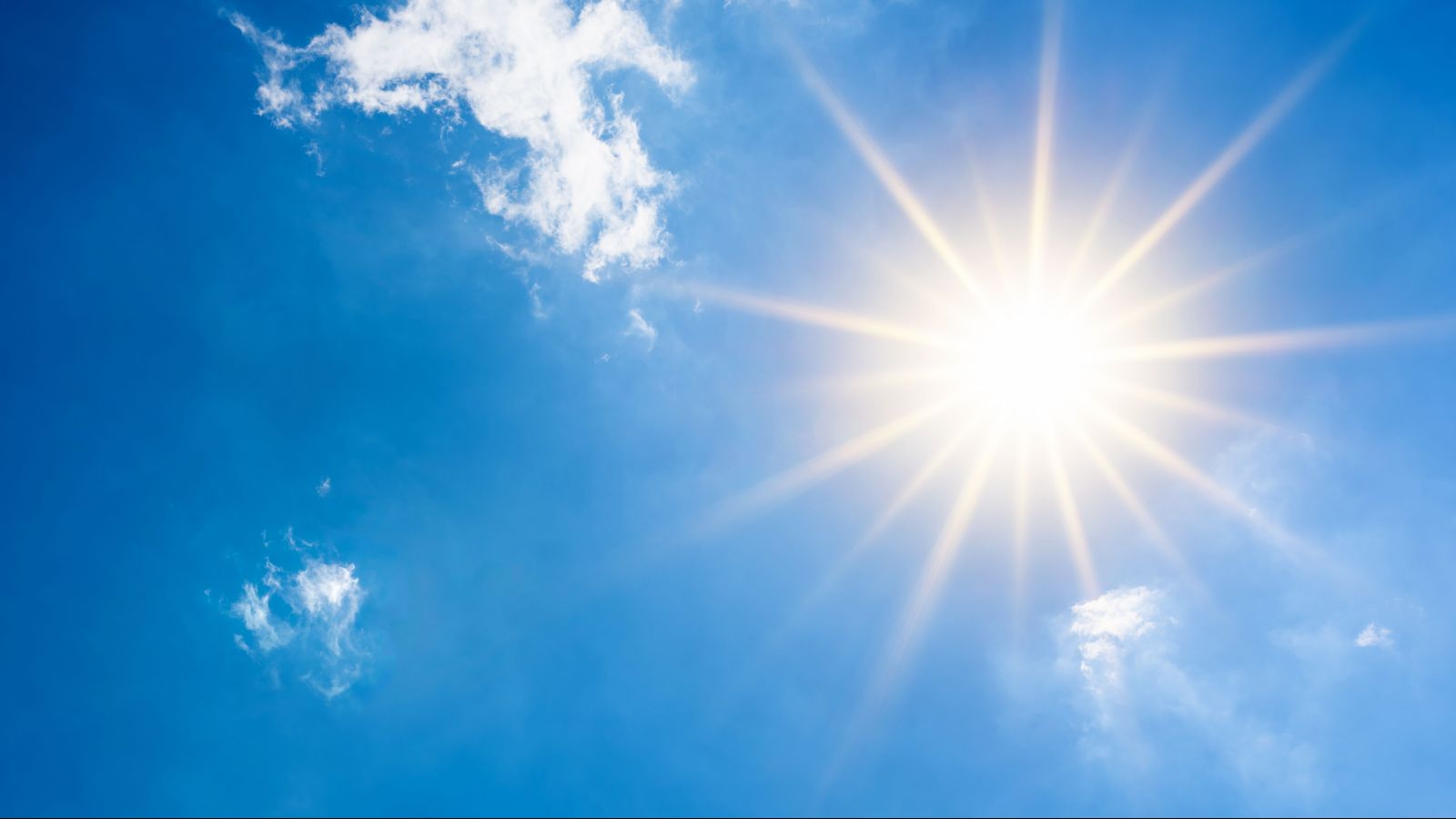 blauer Himmel mit gleißender Sonne und wenigen Schleierwölkchen