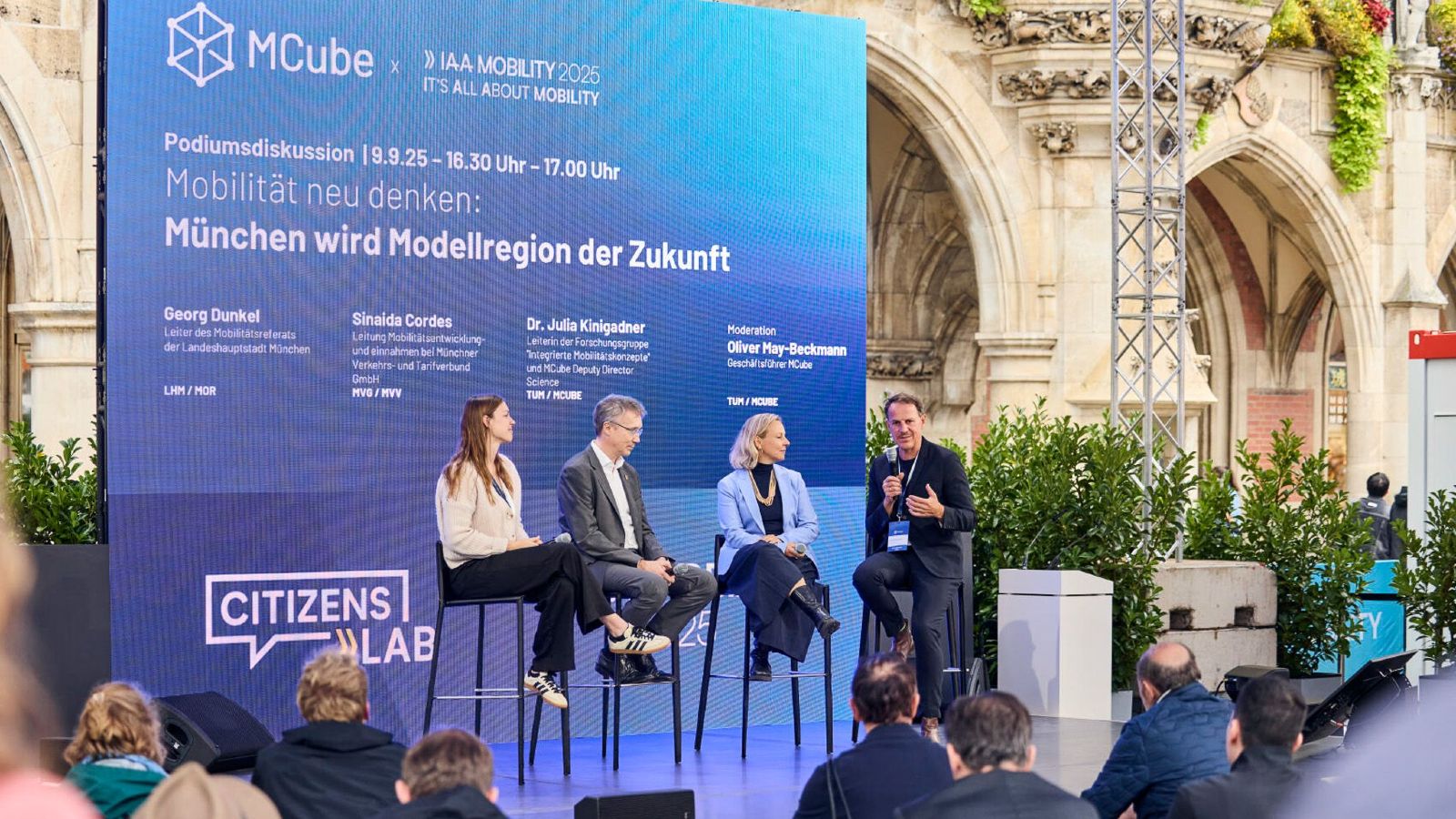 Blick auf die Bühne des Citizens Lab, auf der vier Personen (Dr. Julia Kinigadner, Georg Dunkel, Sinaida Cordes und Oliver May-Beckmann) eine Diskussion über das Thema