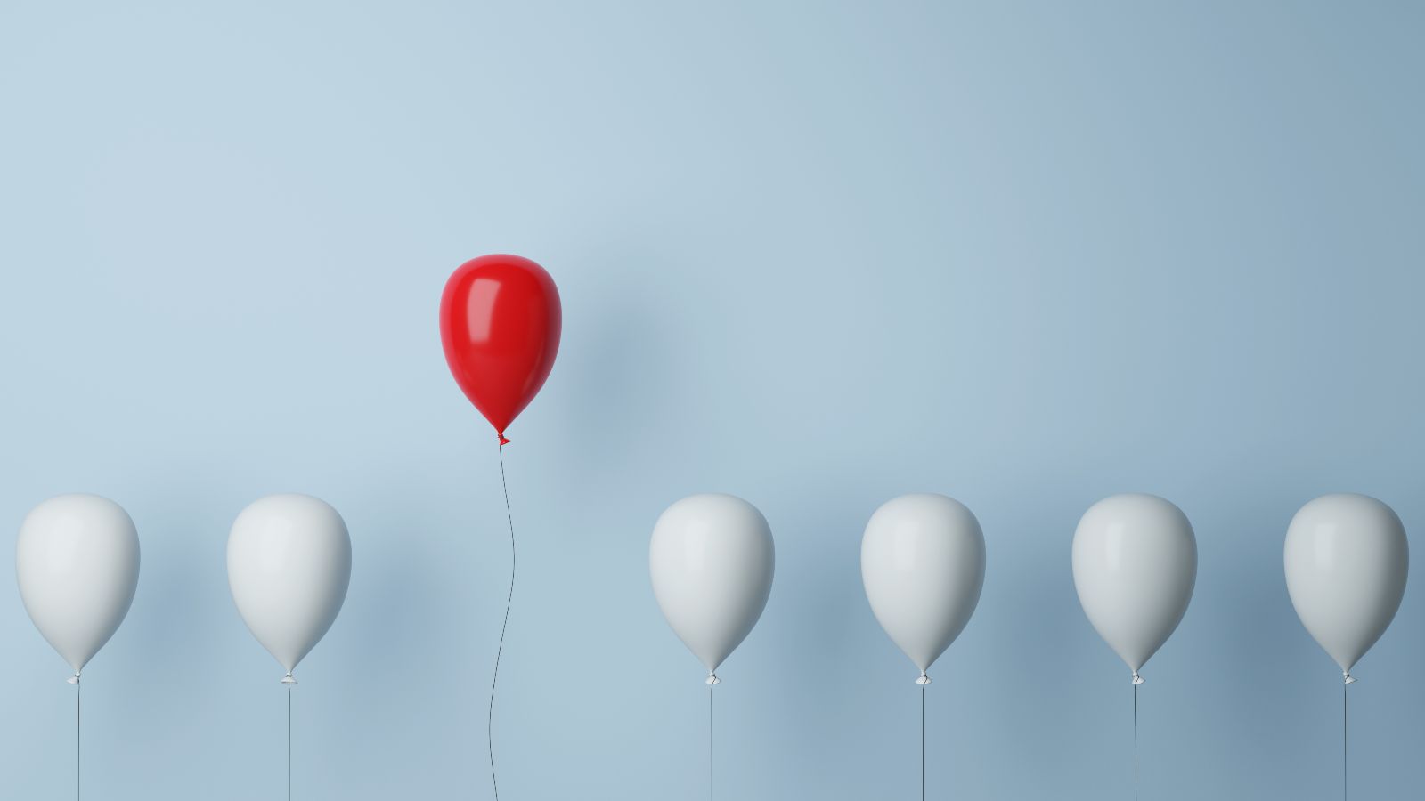 Luftballonreihe in weiß, ein roter steigt auf