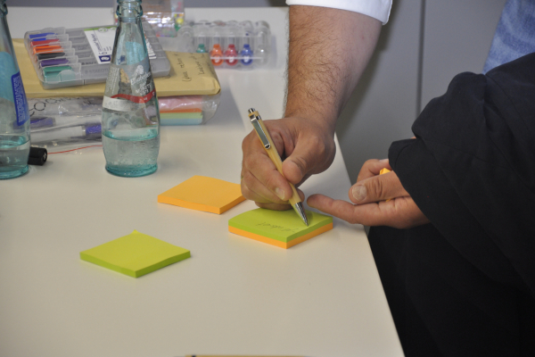 Hand schreibt auf Post-it